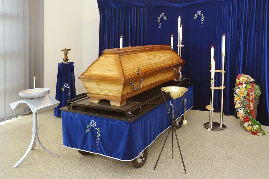 Individuelle Aufbahrung – heller Holzsarg vor blauer Draperie mit Kerzen